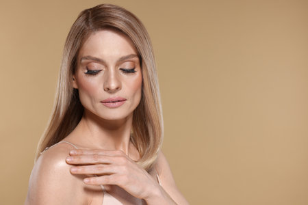 Portrait of beautiful woman with straight blonde hair and stylish makeup on beige background, space for textの写真素材