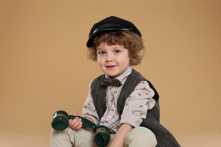 Cute little boy with telephone handset on beige backgroundの写真素材