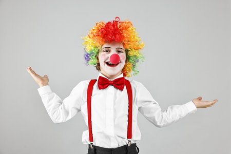 Happy little boy in clown wig and red nose on grey background. Surprise partyの写真素材
