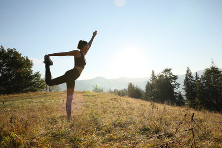 Woman practicing yoga in mountains at sunrise