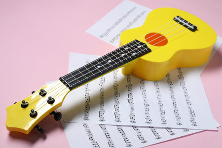 Ukulele and music sheets on pink backgroundの写真素材