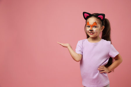 Cute girl with painted face and ears as cat on pink background, space for textの写真素材