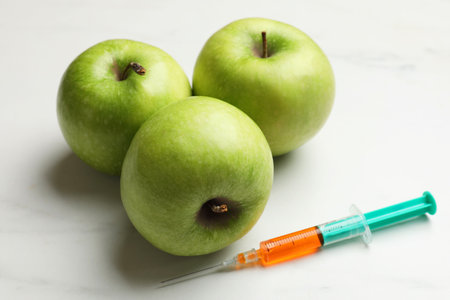 GMO concept. Green apples and syringe on white marble table, closeupの写真素材