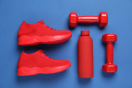 Sneakers, water bottle and dumbbells on blue background, flat lay. Sports equipmentの写真素材
