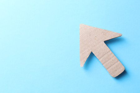 One kraft paper arrow on light blue background, top view. Space for textの写真素材