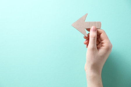 Woman with paper arrow on turquoise background, top view. Space for textの写真素材