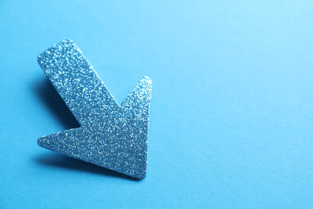 One glitter arrow on light blue background, closeup. Space for textの写真素材