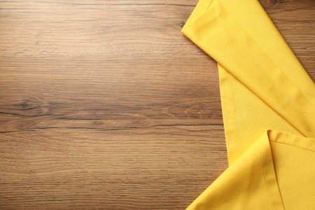 Yellow tablecloth on wooden background, top view. Space for textの写真素材