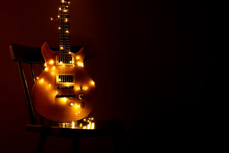 Electric guitar with lights on chair against dark background. Space for textの写真素材