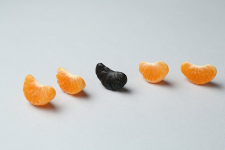 Black tangerine piece among orange ones on light backgroundの写真素材