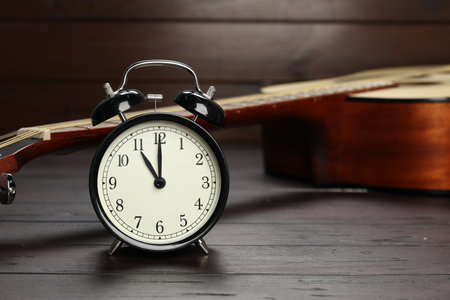 Alarm clock and guitar on wooden backgroundの写真素材