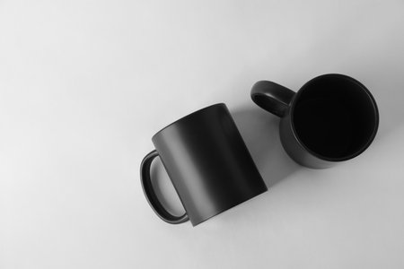 Two blank black mugs on white background, top view. Mockup for designの写真素材