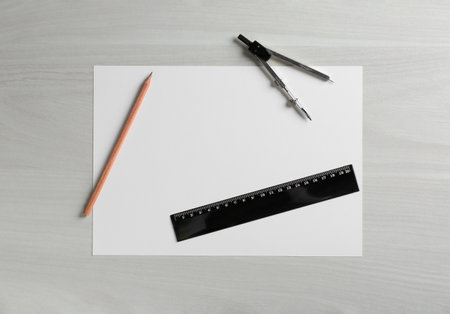 Ruler, paper, compass and pencil on white wooden table, flat lay. Space for text