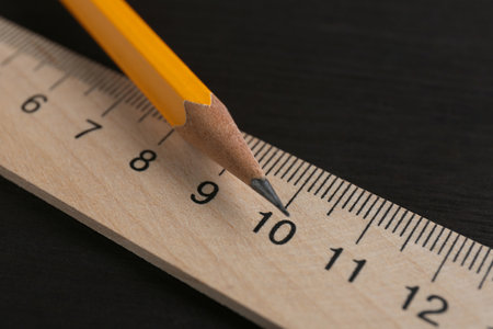 Ruler and pencil on black wooden table, closeupの写真素材