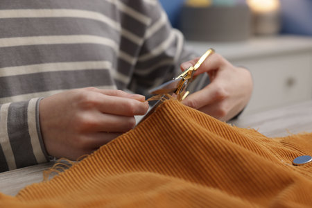 Woman cutting cloth at wooden table indoors, closeup