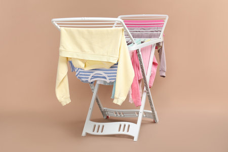 Drying rack with fresh clean laundry on beige background