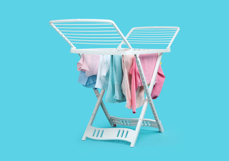 Drying rack with fresh clean laundry on light blue background