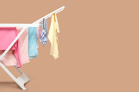 Drying rack with fresh clean laundry on beige background. Space for textの写真素材
