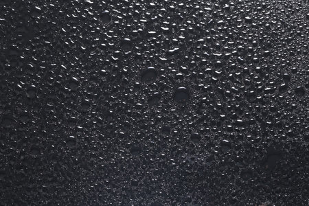 Water drops on dark grey glass surface, top viewの写真素材