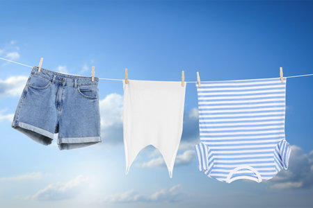 Different clothes drying on washing line against blue sky