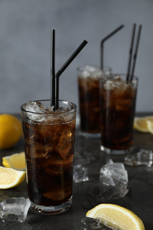 Fresh iced cola and lemon slices on dark grey table