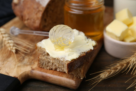 Tasty sandwich with butter, honey and dipper on wooden table, closeupの写真素材