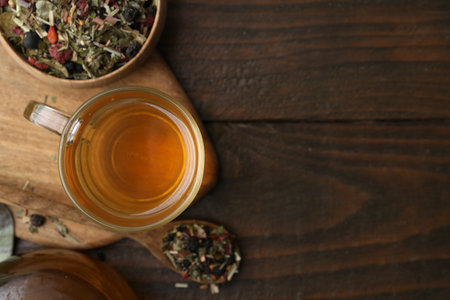 Delicious herbal tea and dry leaves on wooden table, flat lay. Space for textの写真素材