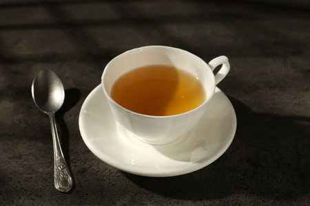 Refreshing green tea in cup and spoon on dark textured table, closeupの写真素材