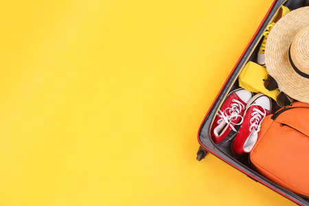 Travel abroad. Packed suitcase on yellow background, top view. Space for textの写真素材