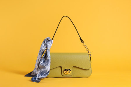 Stylish leather bag with handkerchief on yellow backgroundの写真素材