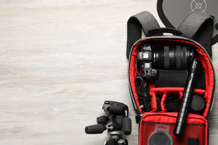 Professional photographer's equipment and backpack on light wooden background, flat lay. Space for textの写真素材