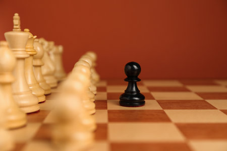 Black pawn in front of other white chess pieces on chessboard. Competition conceptの写真素材