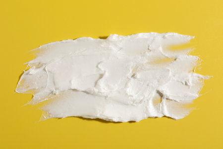 Cream on dark yellow background, top view. Sample of cosmetic productの写真素材
