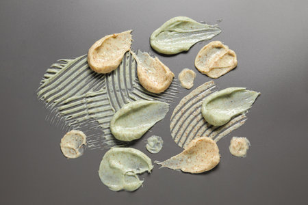 Samples of body scrubs on gray background, flat lay