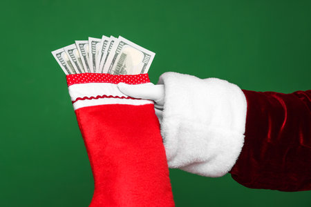 Santa Claus holding stocking with dollar banknotes on green background, closeupの写真素材