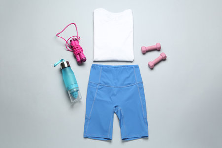 Stylish sportswear, dumbbells and skipping rope on light background, flat layの写真素材