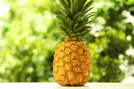 Fresh ripe pineapple on white wooden table against blurred background