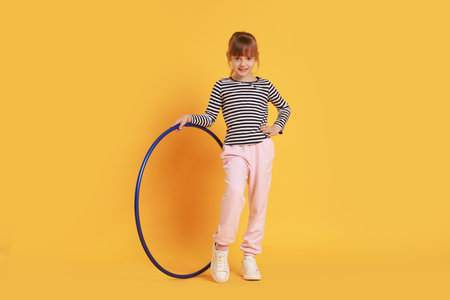Cute little girl with hula hoop on orange backgroundの写真素材