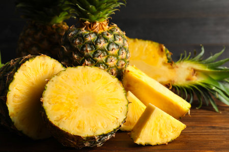 Whole and cut ripe pineapples on wooden table, closeupの写真素材