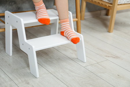 Little girl standing on step stool indoors, closeup.