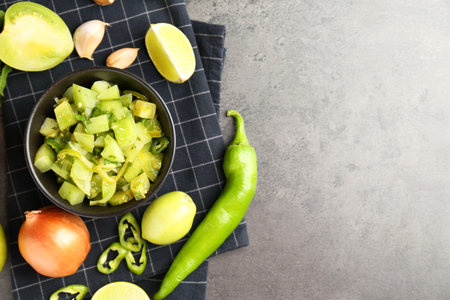 Delicious salsa in bowl and products on grey textured table, flat lay. Space for textの写真素材