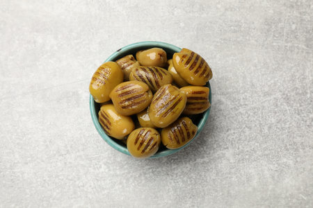 Grilled olives in bowl on gray textured table, top viewの写真素材