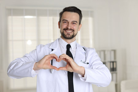 Smiling cardiologist making heart with hands in clinicの写真素材