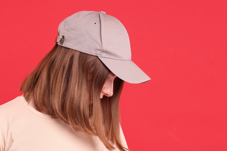 Woman in stylish baseball cap on red background. Mockup for design