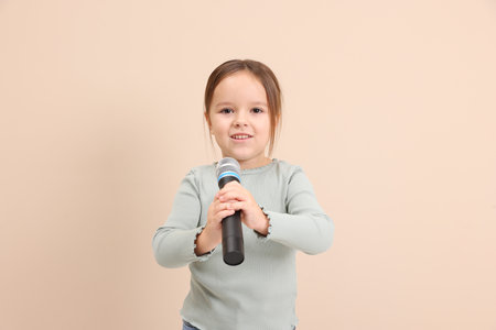 Smiling girl with microphone near beige wallの写真素材