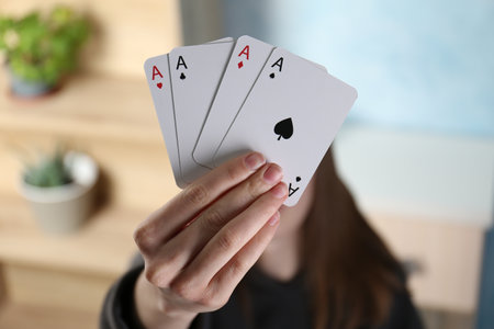Woman with playing card against blurred background, closeup