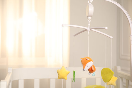 Crib with baby mobile in child's room, space for textの写真素材