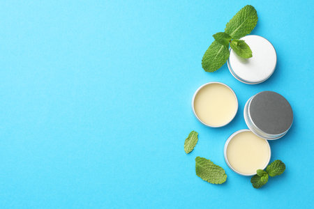 Natural lip balms and mint leaves on light blue background, flat lay. Space for textの写真素材