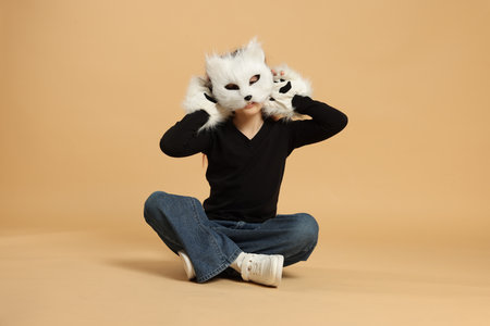 Girl wearing cat mask and gloves on beige backgroundの写真素材