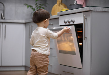 Little boy playing with oven in kitchen. Dangerous situationの写真素材